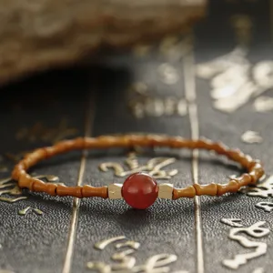 Close-up detail of a Chinese style bamboo-joint olive pit bracelet with a central red agate bead