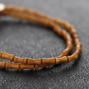 Macro shot showing the detailed texture of bamboo-shaped olive pit beads on a dark background