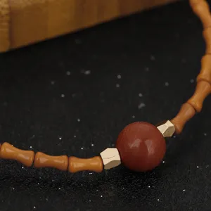 Macro detail of Chinese style olive nut bamboo knot bracelet with red bead and gold accents