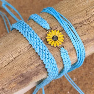 Primer plano de set de pulseras bohemias de hilo encerado azul con dije de girasol