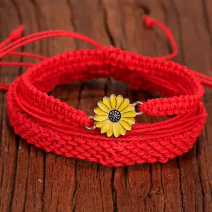 Primer plano del conjunto de pulseras bohemias trenzadas rojas con dije de girasol.