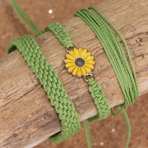 Vista detallada de un juego de pulseras bohemias de hilo de cera verde con una margarita