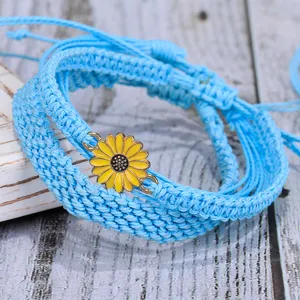 Vista de cerca de la pulsera tejida a mano azul claro con dije de girasol amarillo