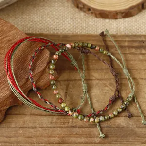 Detail of three handmade braided wax thread bracelets with tiger eye stone beads.