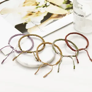 Close-up detail of five colorful handmade braided cotton rope bracelets in ethnic style.
