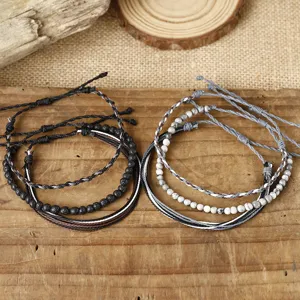 Detail view of two 3-piece sets of handmade braided wax thread bracelets with stone beads.