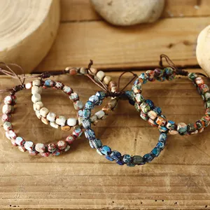 Gros plan de trois bracelets de perles en pierre impériale tissés à la main sur fond de bois.