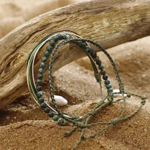 Macro shot of hand-woven wax line bracelets with African turquoise beads on driftwood
