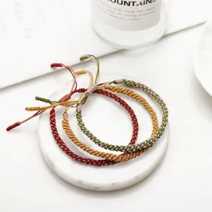 Close-up of three colorful hand-woven corn knot bracelets on a marble tray