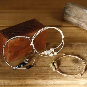 Set mit drei handgefertigten Naturstein-Perlenarmbändern auf rustikalem Holzuntergrund