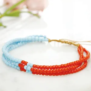 Primer plano de pulsera bohemia multicapa hecha a mano con cuentas en azul claro y naranja.