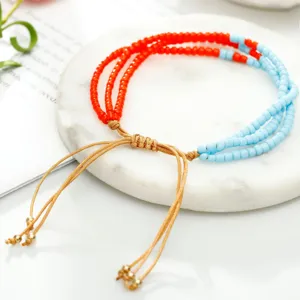 Primer plano de pulsera bohemia de tres capas de cuentas naranjas y azules con cordón.