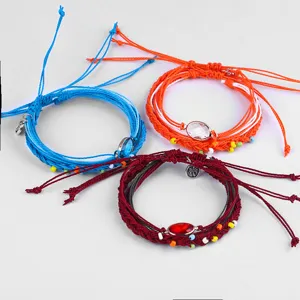 Nahaufnahme von drei farbenfrohen, böhmisch gewebten Wachskordelarmbändern mit Perlen.