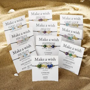 Variety of handmade natural stone wish bracelets on cards presented in a beach setting