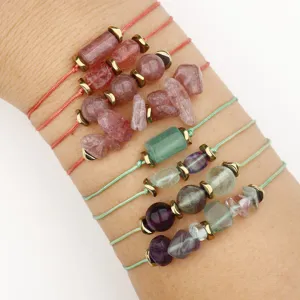 Detail of natural stone bracelets with strawberry crystal and fluorite beads on wrist.
