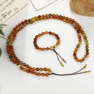 Detailoverzicht van 108 drakenader agaat mala kralen en bijpassende armband op wit vlak
