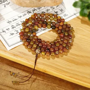 Detail van een mala-ketting met 108 kralen van drakenagaat op een Zen houten achtergrond