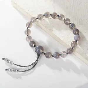 Detailweergave van handgemaakte grijze agaat natuursteen kralenarmband met kwastje.
