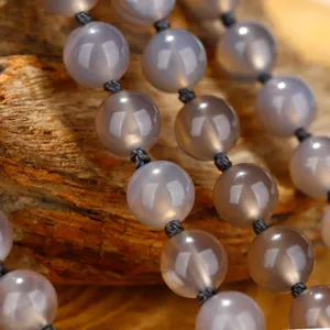 Macro-detail van grijze agaat mala-kralen met geknoopt zwart koord en natuursteen-textuur