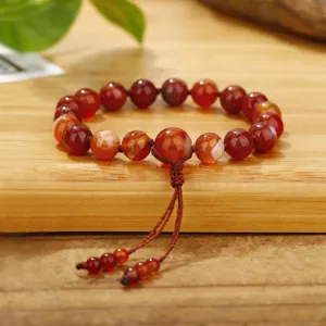 Rode carneool agaat kralen armband met decoratieve kwast op houten ondergrond