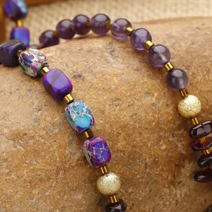 Detalle macro de pulsera de cuentas de jaspe imperial, amatista y granate sobre piedra