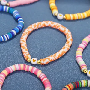 Nahaufnahme von bunten Heishi-Perlenarmbändern aus Polymer-Ton im Boho-Stil mit Herz-Anhängern