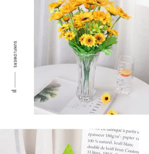 Gros plan détail d'un bouquet de tournesols artificiels dans un vase en verre transparent.