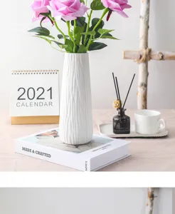 Detailed view of artificial pink rose bouquet in a white ceramic vase, elegant home decor setup.