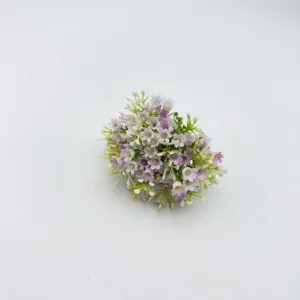Close-up detail of small artificial purple and white flowers with green stems for DIY crafts.