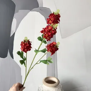 Détail de tige de fleur rouge artificielle, arrangement floral décoratif pour maison et événements.