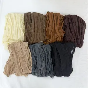 Detailed view of women solid color crinkled voile long scarves in multiple rich earth tones.