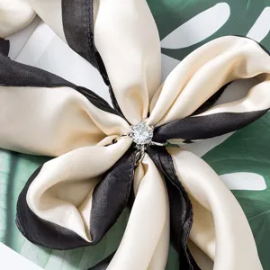 Λεπτομερής λήψη μιας αστραφτερής μεταξωτής πόρπης μαντηλιού που κρατάει κομψό σχέδιο.