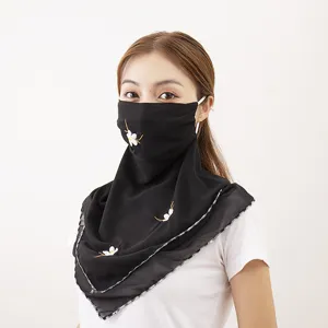 Detailed close-up of a black chiffon sun protection face veil with delicate white embroidery.