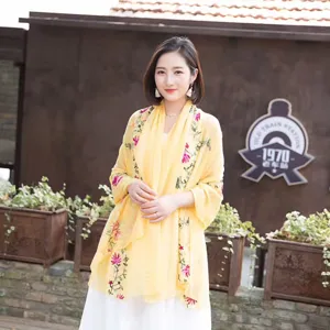 Detailed outdoor scene showing ethnic embroidered cotton linen shawl scarf in yellow.