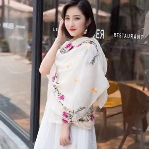 Detailed shot of a white cotton linen floral embroidered scarf shawl, perfect for travel outfit style.