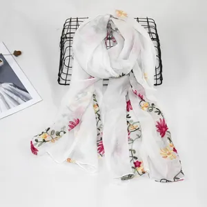 Detailed view of white floral embroidered cotton linen scarf, elegant bohemian style shawl.