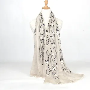 Elegant beige cotton linen scarf with delicate black and white floral embroidery details.