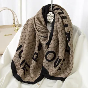 Detailed close-up view of pleated winter scarf featuring monogram pattern and bold letter print.