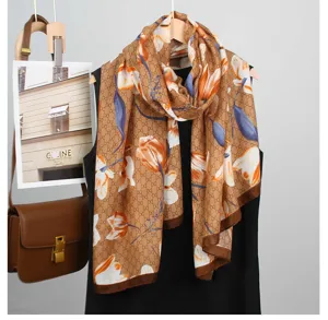 Vista dettagliata della sciarpa marrone da donna con stampa floreale e monogramma di lusso.