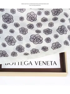 Detail view of white scarf with grey camellia floral pattern, elegant drape and soft texture.