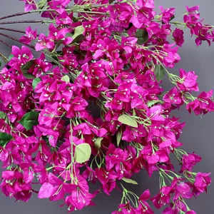 Close-up view of vibrant magenta artificial bougainvillea petals with lush green leaves
