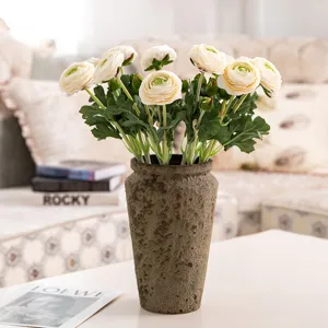 Bouquet de renoncules artificielles floquées dans un vase texturé vintage pour déco.