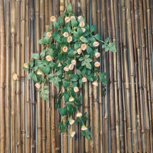 Gros plan sur la vigne de rose artificielle, fleurs roses et feuilles vertes, texture en détail.