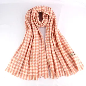 Detailed view of soft houndstooth pattern scarf in pink and white with tassels