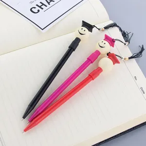 Set de bolígrafos creativos de graduación con cara sonriente y borlas sobre un cuaderno
