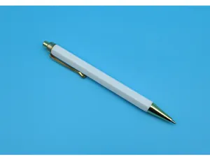 Close-up view of a white hexagonal click-action ballpoint pen with elegant gold metal details