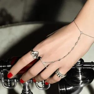 Close-up detail of luxury 925 sterling silver hand chain with zircon-paved heart rings