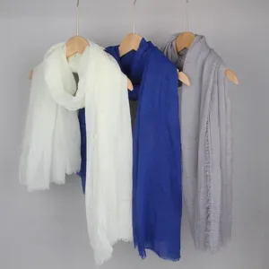 Solid color cotton linen scarves in white, blue, and grey hanging on wooden hangers