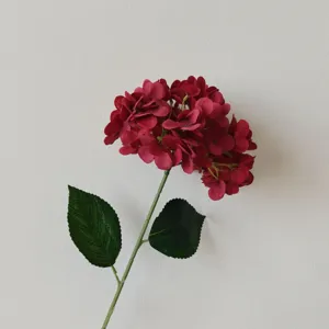 Detailed view of a dark red artificial hydrangea flower with realistic green leaves.