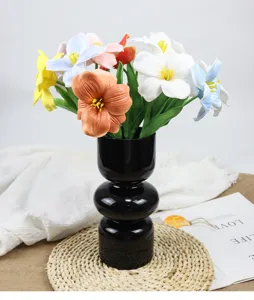 Detailed macro view of colorful artificial brownie open tulips in a black vase.